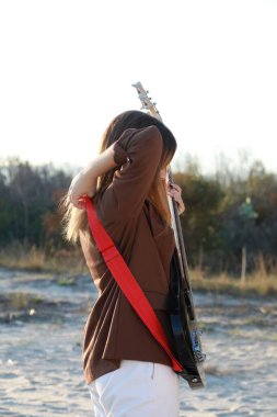 Sahilin yanındaki doğada bas gitar çalan bir kız..