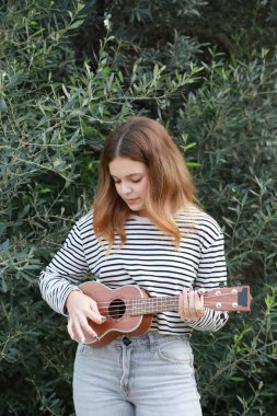 Mutlu kız doğada gitar çalıyor..