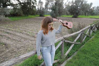 Mutlu kız doğada gitar çalıyor..