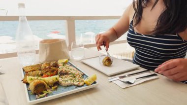 Izgara balık alıp servis etmek için maşa kullanan bir kadın. .