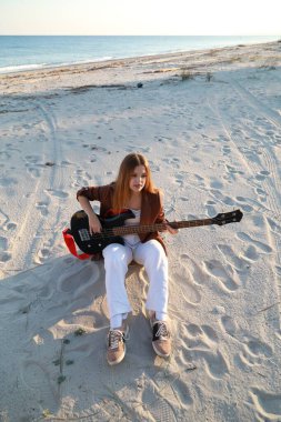 Sahilin yanındaki doğada bas gitar çalan bir kız..