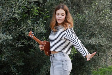 Mutlu kız doğada gitar çalıyor..