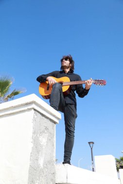 Genç Uzun Saçlı Adam Klasik Gitar Çalıyor Dışarıda, Düşük Açı.