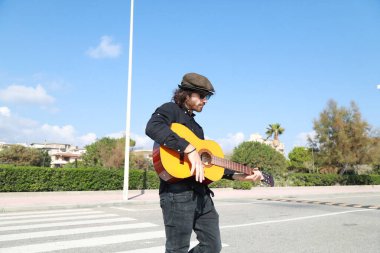 Genç adam, yazın yaya geçidinde gitar çalıyor..