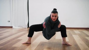 İtalyan kadın strese karşı egzersiz yapıyor yalınayak dans ediyor ve kendine yoğun bir şekilde bakıyor..