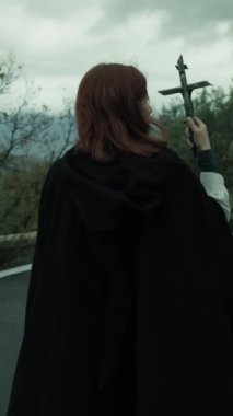 Bulutlu bir günde kırsalda pelerinli genç bir kadın..