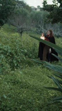 Bulutlu bir günde kırsalda pelerinli genç bir kadın..