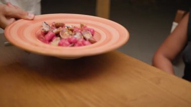 Plaj restoranında akşam yemeği için renkli hamur tatlısı servisi yapan garson..