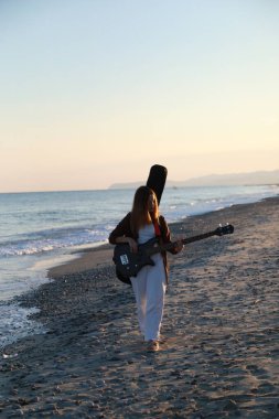 Sahilin yanındaki doğada bas gitar çalan bir kız..