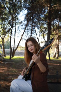 Sahilin yanındaki doğada bas gitar çalan bir kız..