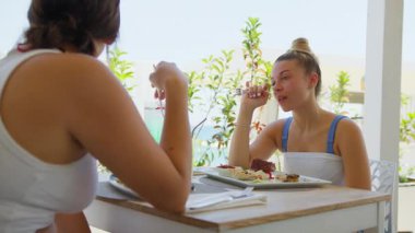 İki kız kardeş sahilde bir gün geçirdikten sonra otelde öğle yemeği yiyorlar. . 