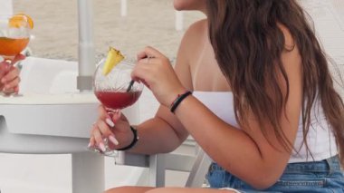 Arkadaşlar konuşuyor ve sahilde kokteyl içiyor.. 