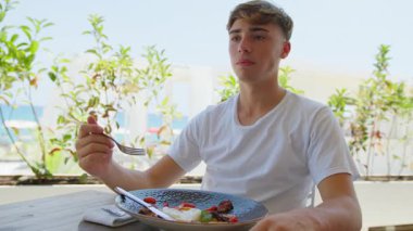 Sahildeki restoranda öğle yemeği yiyen adamın üzerine güneş. . 