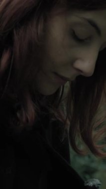 Bulutlu bir günde kırsalda pelerinli genç bir kadın..