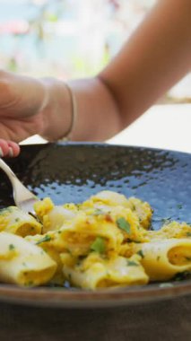 Kumsalda öğle yemeğinde makarna yiyen ve gülen bir kadın. .