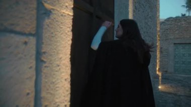Gizemli genç kadın pelerin ve fenerle bir köyün sokaklarında yürüyor..