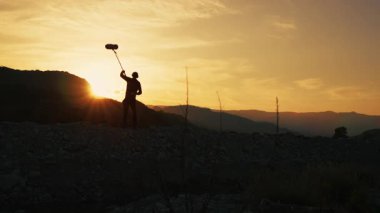 Ses kayıt uzmanının silueti dağlarda arka plan doğasını yakalıyor..