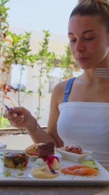 Yaz boyunca sahilde öğle yemeğine başlamak için çatal ve bıçak kullanan bir kadın. .