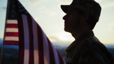 Anma Günü için gün batımında Amerikan Bayrağı önünde Bir Askerin Silüeti