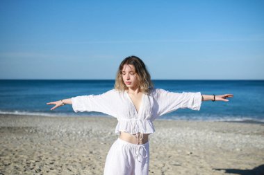 Kısa saçlı kız yazın okyanus kıyısındaki sahilde egzersiz yapıyor. .