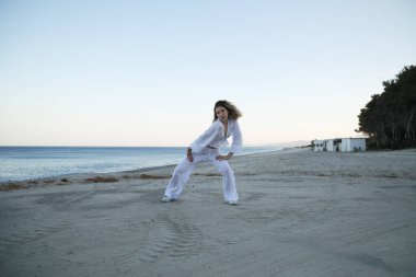 Yazın gün batımında sahilin kenarında beyaz giysili hip hop dansçısı kız. .