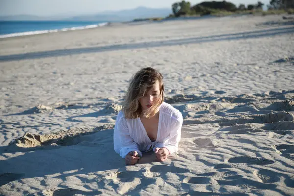 Yazın okyanusun kenarında Akdeniz kumu üzerinde beyaz giyinmiş bir kız. .