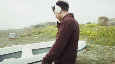 Sahildeki adam kulaklıkla müzik eşliğinde dans ediyor. . 