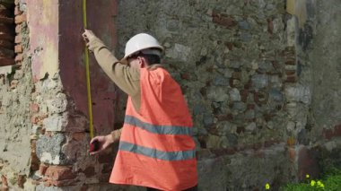 Yeniden inşa etmek için eski bir duvarın yüksekliğini ölçen mühendis.. 