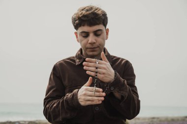 Adam kışın kıyıda tespih ve gözleriyle dua ediyor. . 