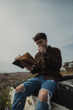 Hıristiyan adam sahildeyken İncil 'de dua okuyor. . 