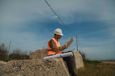 Bir kayanın üzerinde oturmuş not alan bir mühendis. . 