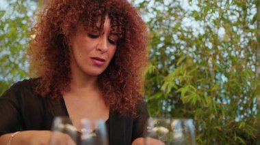 Dışarıdaki bir otelde yemek yerken gülümseyen ve gülen bir kadın. . 