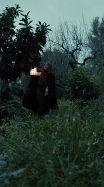 Bulutlu bir günde kırsalda pelerinli genç bir kadın..