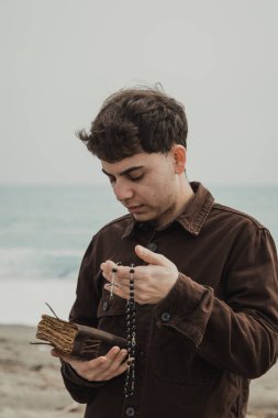 Hıristiyan adam sahildeyken İncil 'de dua okuyor. . 