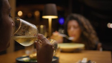 Bir arkadaşla yemek yerken kadehte şarap içen bir kadın. . 