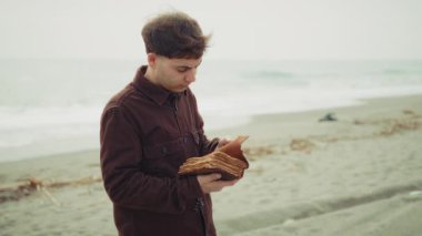 Adam İncil okuyor ve sahildeki sayfaları çeviriyor. . 