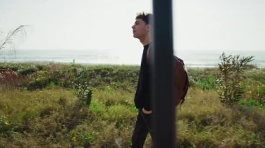 Adam işten sonra sırt çantasıyla deniz kenarında yürüyor. . 