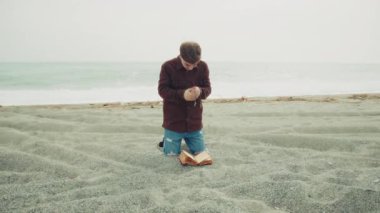 Sahilde İncil 'le dua eden adam .