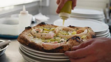 Şef, sıcak ahtapot pizzasının üstüne son parça yağ koyuyor. . 