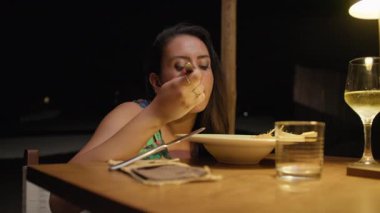 Dışarıdaki restoranda yemek yiyen bir kadın. Ilık ışığın altında. . 