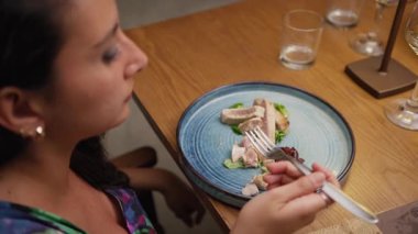 Lokantadaki gurme ton balığını yemek için çatalı kullanan bir kadın..