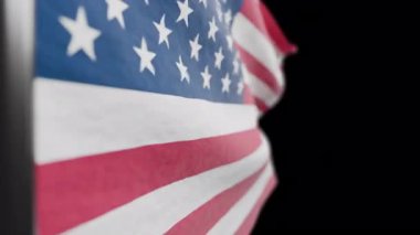 Amerika Birleşik Devletleri bayrağını siyah alfa arka planda sallıyor.