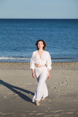 İtalyan Kız Beyaz Giysiler İçinde Okyanus 'un yanındaki yumuşak plajda Dans Ediyor .