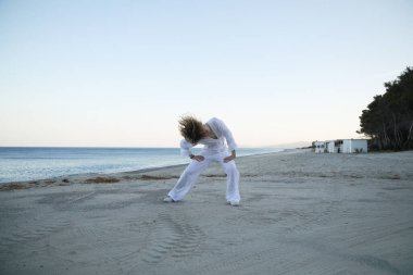 Yazın gün batımında sahilin kenarında beyaz giysili hip hop dansçısı kız. .