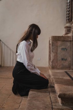 Kilisede diz çöküp dua eden bir kadın. . 