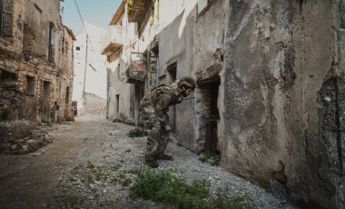 Asker, eski bir evin yıkılmış kapısından bakar.. 