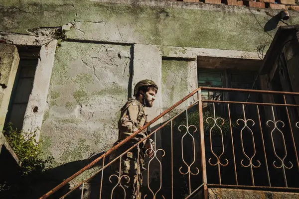 Asker bombalarla harap olmuş eski bir evin merdivenlerine tırmanıyor.. 