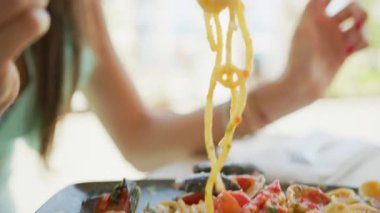 Deniz ürünleriyle spagetti toplamak için çatal kullanan bir kadın. . 