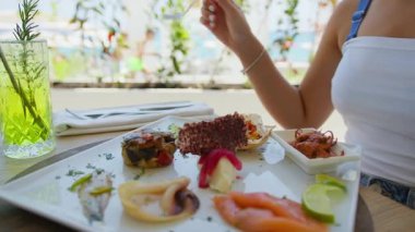 Aç kadın çatalı alır ve öğle yemeği için oteldeki balıkları yemeye başlar. .