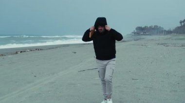 Kışın denizdeki adam rüzgardan korunmak için başlığını takar.. 